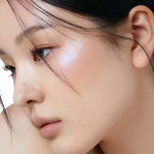 Close-up of a woman showcasing Laka Dreambeam Highlighter, highlighting a radiant and dreamy glow on her skin.