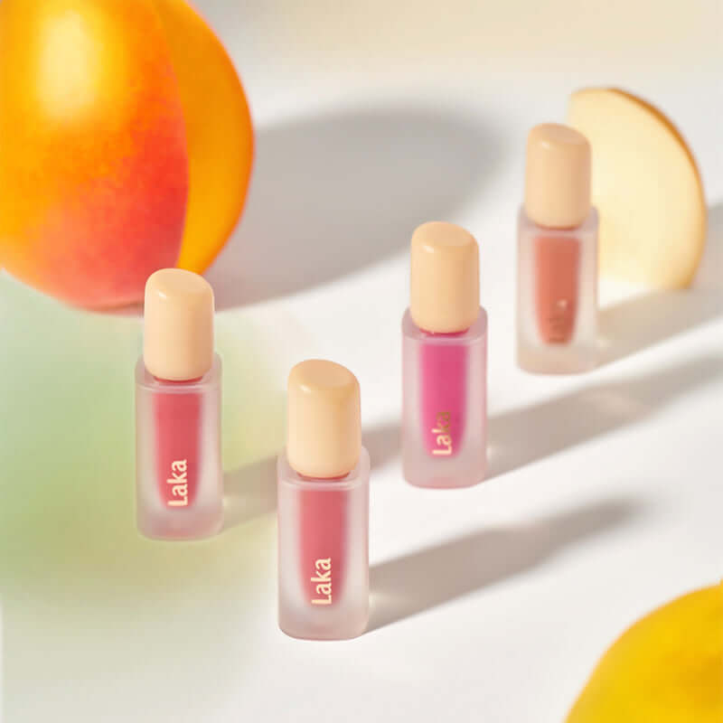 Laka Fruity Glam Tint bottles surrounded by vibrant fruit, showcasing juicy and glossy lip color options.