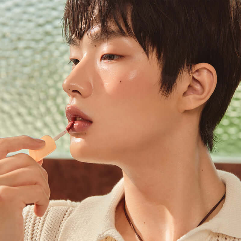 Model applying Laka Fruity Glam Tint lip gloss, showcasing a glossy, natural look with juicy color and shine.