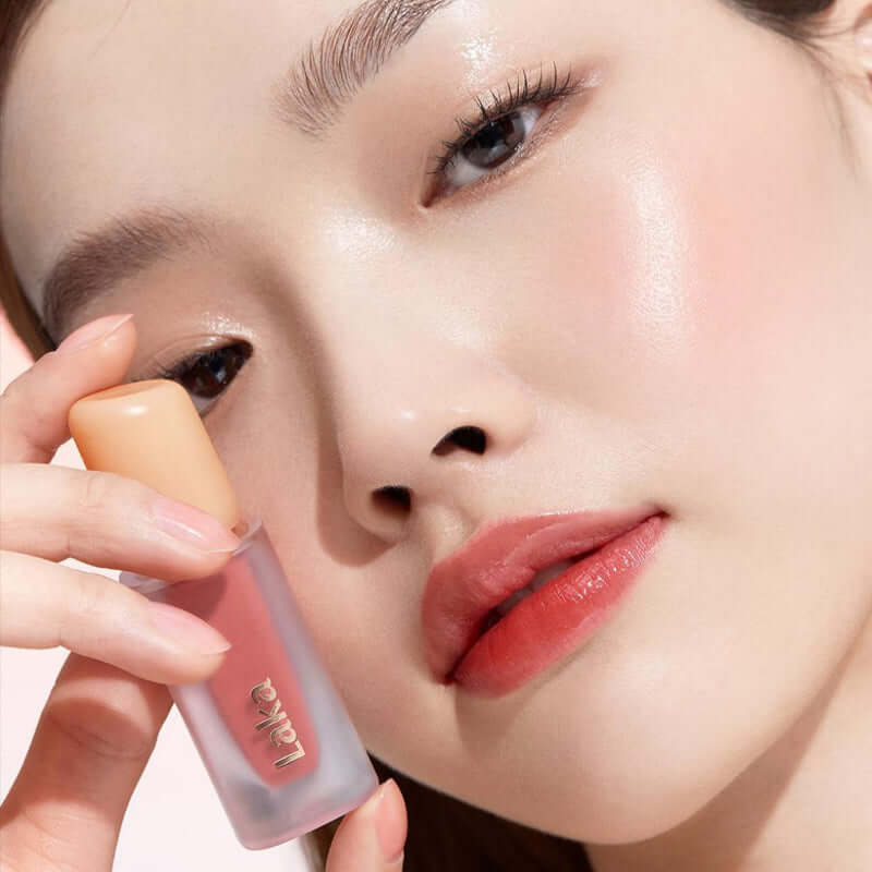 Close-up of a woman showcasing Laka Fruity Glam Tint lip gloss for a juicy, high-shine finish.