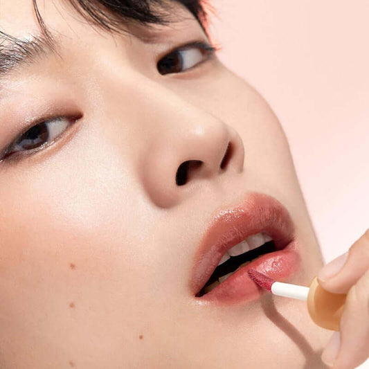 Close-up of a person applying Laka Fruity Glam Tint for a juicy, high-shine lip color with semi-sheer finish.