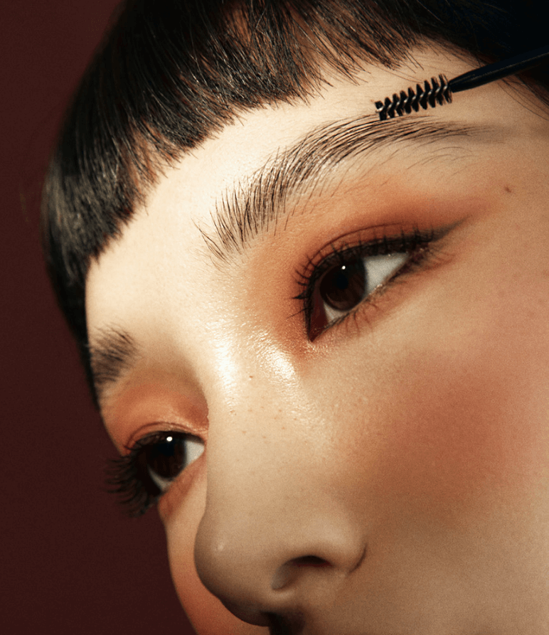 Close-up of a person shaping brows with a brow gel for a defined look, showcasing neat, well-groomed brows.