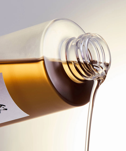 Beauty of Joseon Ginseng Cleansing Oil pouring from bottle, showcasing its thin, water-like consistency.